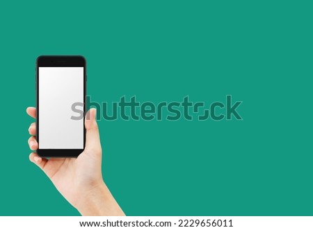 Hand holding black smartphone isolated on green background