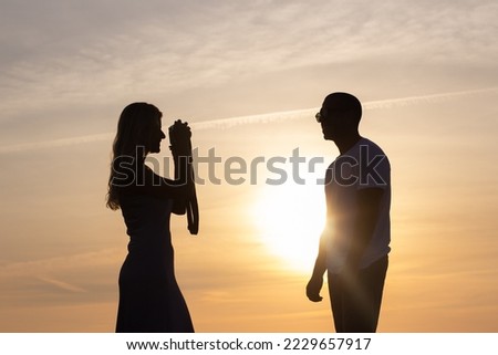 Focused woman photographing husband on beach. Man posing, wife holding old-fashioned camera and taking pictures at dusk. Hobby, family concept