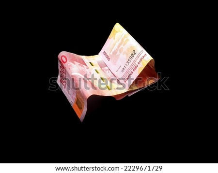 one hundred thousand rupiah, Indonesian currency, isolated against black background.