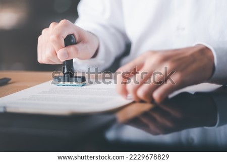 Businessman validates and manages business documents and agreements, signing a business contract approval of contract documents confirmation or warranty certificate,approval stamp Royalty-Free Stock Photo #2229678829
