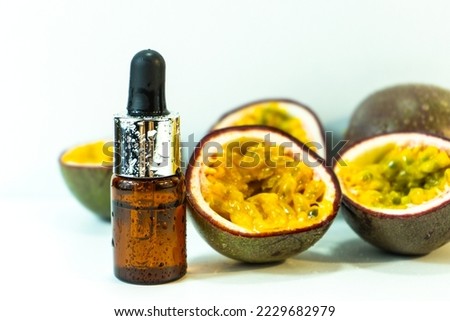 Passion fruit essential oil in a brown glass bottle, alternative medicine. Natural organic essence. Passion fruit seed oil and fresh passion fruit on a white background. Selective focus.