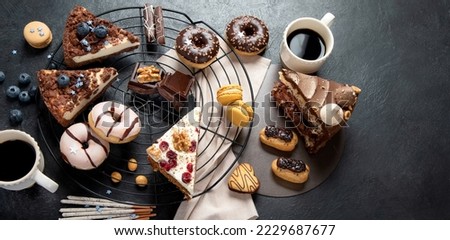 Table with various cookies, donuts, cakes, cheesecakes on dark background.  Delicious dessert table. Top view, flat lay, copy space