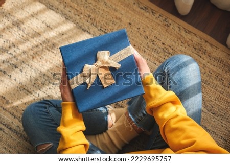 Top view of a young woman holding and receiving a present box at home