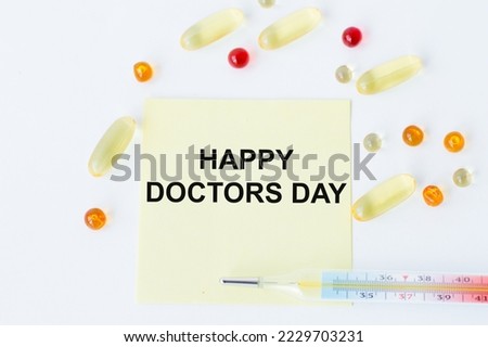 Happy Doctor's Day text on a yellow card on a white background next to a thermometer and tablets