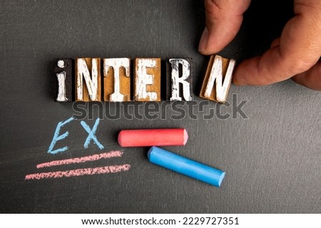 Intern and Extern concept. Wooden letter blocks on blackboard background.