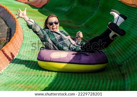 Happy woman rolling down the tubing track on a sunny day