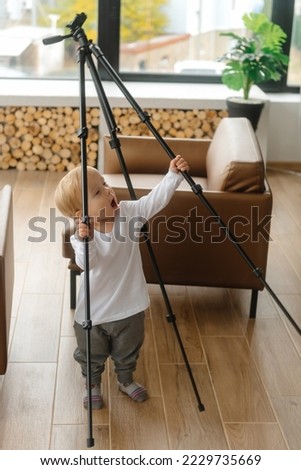 A child blogger holds a video tripod and prepares to become a young blogger