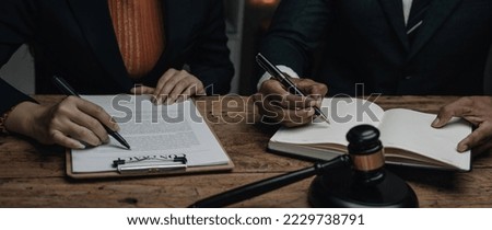 Close up lawyer businessman working or reading lawbook in office workplace for consultant lawyer concept.Lawyer working at table in office, focus on scales of justice