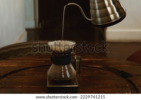 Pouring water from kettle into cup with coffee and wave dripper in cafe, closeup