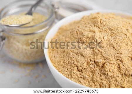 Sesame flour in ceramic bowl on white table, closeup