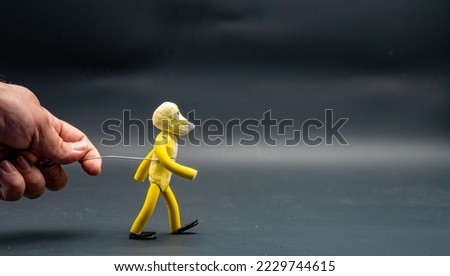 Stopmotion process of walking. Man's hand holding with an aluminum wire a figure made with yellow modeling paste starting the process of walking. The 12 principles of animation.