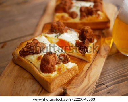 Baked dish of fried chicken on a piece of bread, then topped with an egg and cheese.