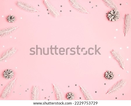 Christmas frame made of white fir branches, cones and stars on pink background. Copy space, top view.