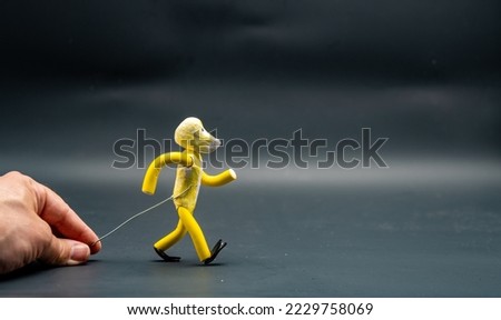 Stopmotion process of walking. First step. Man's hand holding with an aluminum wire a figure made with yellow modeling paste starting the process of walking. The 12 principles of animation.