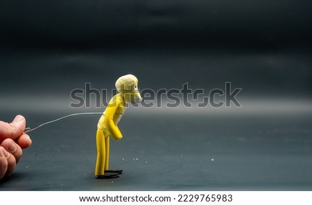 Stopmotion process of jumping. Preparing to jump. Man's hand holding with an aluminum wire a figure made with yellow modeling paste starting the jumping process. The 12 principles of animation.