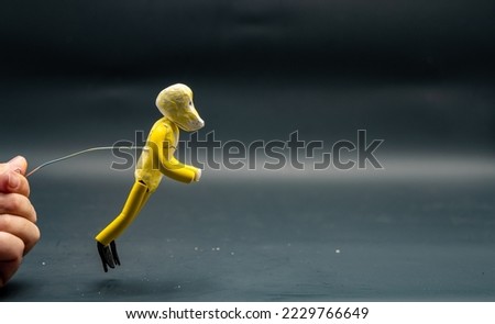 Stopmotion process of jumping. Jump start. Man's hand holding with an aluminum wire a figure made with yellow modeling paste starting the jumping process. The 12 principles of animation.