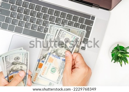 Male freelancer counting dollars in office. Working on laptop or computer. Online business. Make money on the Internet.