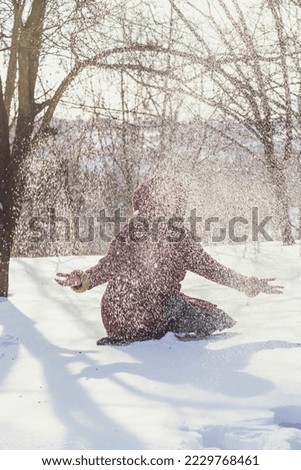 Wintertime fun scenic photography. Throwing snow in air. Picture of woman with winter forest on background. High quality wallpaper. Photo concept for ads, travel blog, magazine, article
