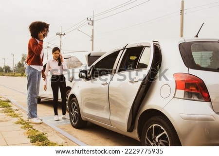 Young asian woman and african american woman driving recklessly in a road accident rear end car damage using smartphone to call car insurance company to take action and negotiate reimbursement. Royalty-Free Stock Photo #2229775935