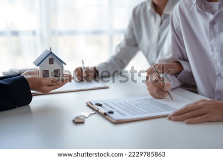 Real estate agent and customer make contract to buy and sell house and land approval of a contract to buy or sell a home offers mortgage loans and home insurance concept. Royalty-Free Stock Photo #2229785863