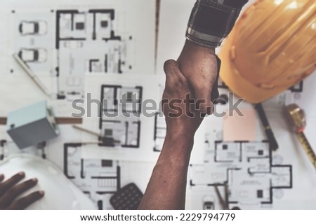 Architect and engineer construction workers shaking hands after finish an agreement in the office construction site, success collaboration concept