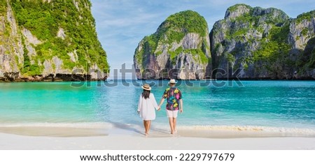 Thai women and caucasian men with a hat walk on the beach of Maya Bay beach Koh Phi Phi Thailand Royalty-Free Stock Photo #2229797679
