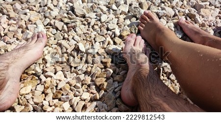 View of legs of young girl and boy on croatian beach, pebble beach, lower part of human body, photo