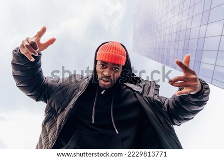 urban street fashion bottom view portrait of a modern african american hip hop cool rapper under skyscraper