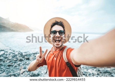 Handsome young man with backpack taking self portrait outside - Happy tourist enjoying summer vacation at the beach - Tourism, technology and journey concept