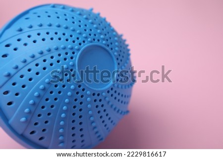 Laundry dryer ball on pink background, closeup. Space for text