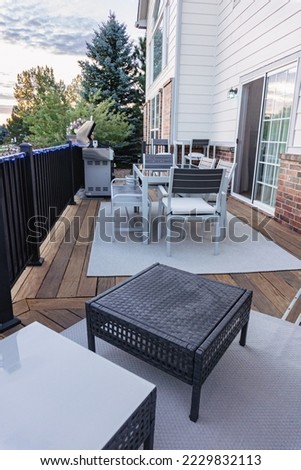 Morning on a summer day. Fully furnished backyard patio with a grill, sitting area, and umbrella.