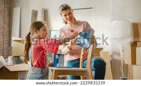 Moving in and Home Renovations: Happy Mother Painting Vintage Furniture Chair Daughter Tries to Help Her. Cheerful Young Family Make Apartment Cozy with Art, Color. Smiles and Happiness Royalty-Free Stock Photo #2229835239