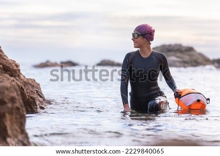Woman swimming in open water with wetsuit and buoy Royalty-Free Stock Photo #2229840065