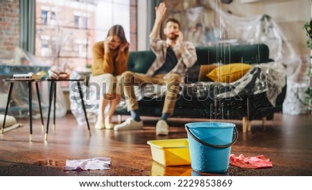 Roof is Leaking, Pipe Rupture at Home: Angry Couple Calling Insurance Company, Screaming into Phone in Frustration, Trying to Find Plumber, Master. Water Drips into Buckets in Living Room. Rack Focus Royalty-Free Stock Photo #2229853869