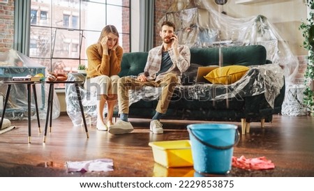 Roof is Leaking, Pipe Rupture at Home: Angry Couple Calling Insurance Company, Screaming into Phone in Frustration, Trying to Find Plumber, Master. Water Drips into Buckets in Living Room. Rack Focus Royalty-Free Stock Photo #2229853875