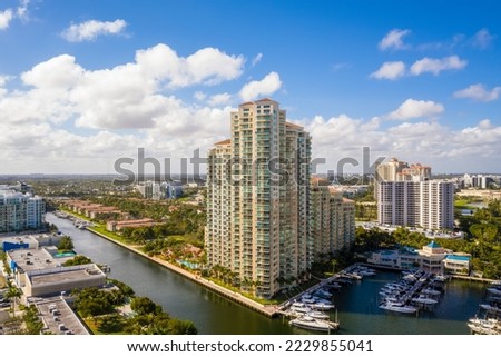 Aerial drone view of Miami bay with city in the background, blue sky, tropical vegetation with trees and palms, pier with bay boats, yachts