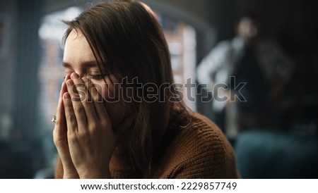 Portrait of Sad Crying Woman being Harrased and Bullied by Her Partner. Couple Arguing and Fighting Violently. Domestic Violence and Emotional Abuse. Rack Focus with Boyfriend Screaming in Background Royalty-Free Stock Photo #2229857749