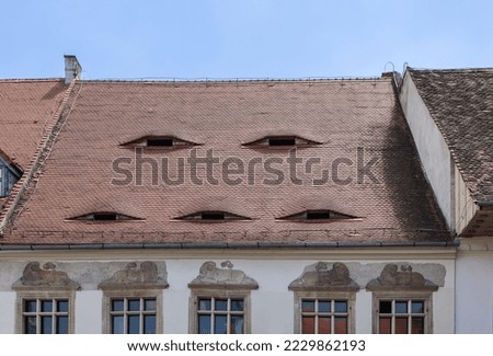 These Sibiu Eyes windows look unnervingly like real eyes, giving houses chilling, anthropomorphic gaze, they have become symbol of protest in Romania, under banner - We see you Royalty-Free Stock Photo #2229862193