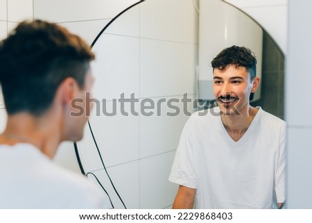 Man looks at himself in the mirror Royalty-Free Stock Photo #2229868403