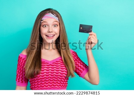 Photo of pretty charming schoolgirl wear pink crop top rising credit card empty space isolated turquoise color background