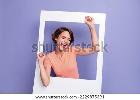 Photo of cheerful overjoyed lady eyes closed raise hand enjoy success champion scream yes hooray isolated on purple color background