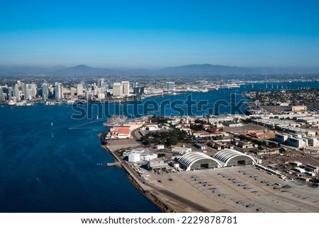 Aerial view of North Island Naval Air Base on Coronado and downtown San Diego California while flying over the bay with boats on the water and mountains in the background during daylight Royalty-Free Stock Photo #2229878781