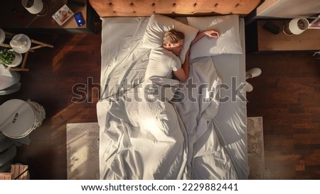 Top View Home: Handsome Young Man Sleeps in His Bed in a Stylish Bedroom, Sun Shines on Him. Morning Concept. Peaceful Sleeping and Relaxation, Important for Wellness . Top Down Above Shot Royalty-Free Stock Photo #2229882441