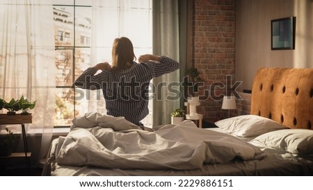 Beautiful Young Woman Waking up in the Morning, Stretches and Gets Out of Bed, Sun Shines From the Apartment Window, Ready for Opportunities, Achievements, Adventures. Medium Shot Royalty-Free Stock Photo #2229886151