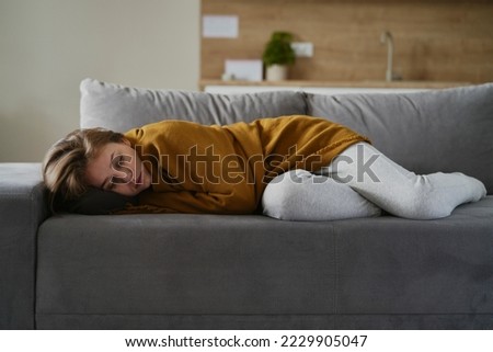 Caucasian terrified woman lying on the sofa under the blanket Royalty-Free Stock Photo #2229905047