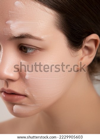 Beautiful woman applying moisturizer cream on her face. Photo of smiling woman with perfect makeup on pink background. Beauty concept