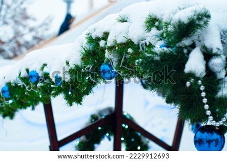 Snowdrifts of heavy snow lie on the green branches of the Christmas tree. The concept of how to safely decorate the facades of buildings on the street in winter.