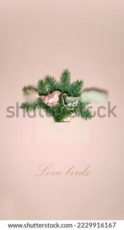 Christmas composition. Pink envelope with pine tree, pink and silver bird ornaments on pastel table background. Flat lay, top view, copy space. Happy New Year card. Pink Christmas. Love birds.