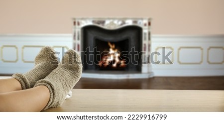 Woman legs with socks and home interior with fireplace. 