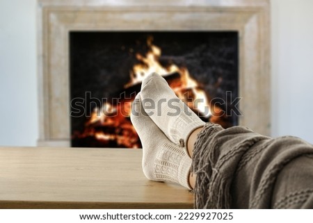 Woman legs with socks and fireplace background. 